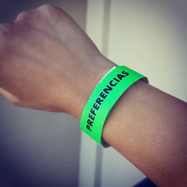 Pulsera verde flúo puesta en una muñeca, impresa con la palabra PREFERENCIAS